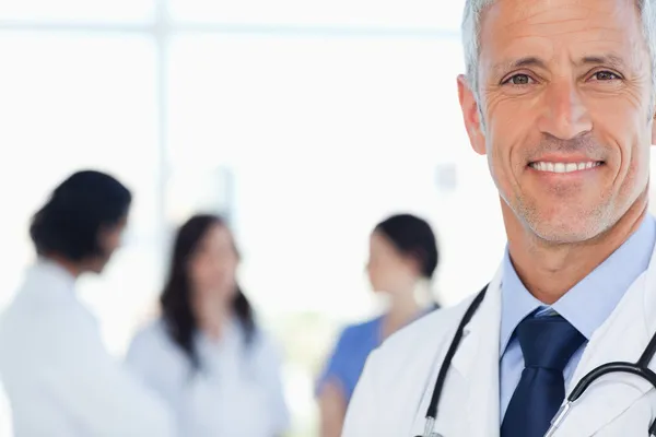 Uśmiechający się lekarz z jego medyczne staże za nim — Zdjęcie stockowe