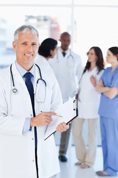 Médico sonriente señalando una palabra en su portapapeles — Foto de Stock