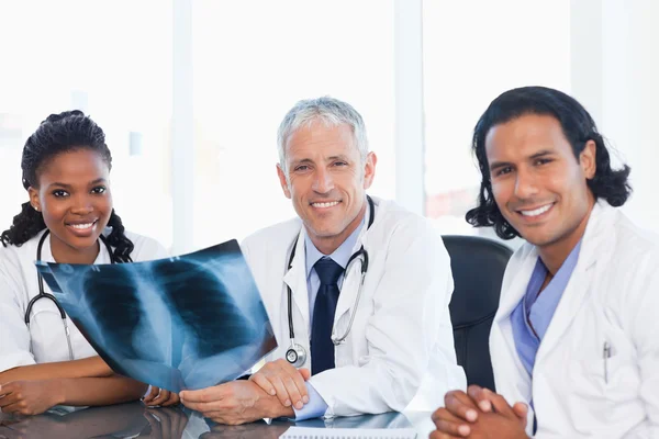 Ärzteteam lächelt bei der Arbeit am Röntgenbild eines Patienten — Stockfoto