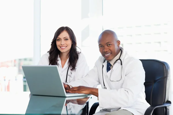 Zwei Krankenschwestern arbeiten ernsthaft während sie am Schreibtisch in einem Brunnen sitzen — Stockfoto