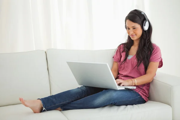 Estudante latino usa fone de ouvido usando um laptop — Fotografia de Stock