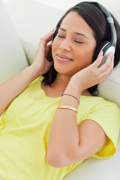 Close-up of a smiling Latino enjoying music on a smartphone — Stock Photo, Image