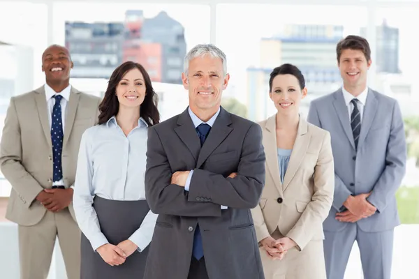 Mature smiling manager standing upright and crossing his arms in Royalty Free Stock Photos