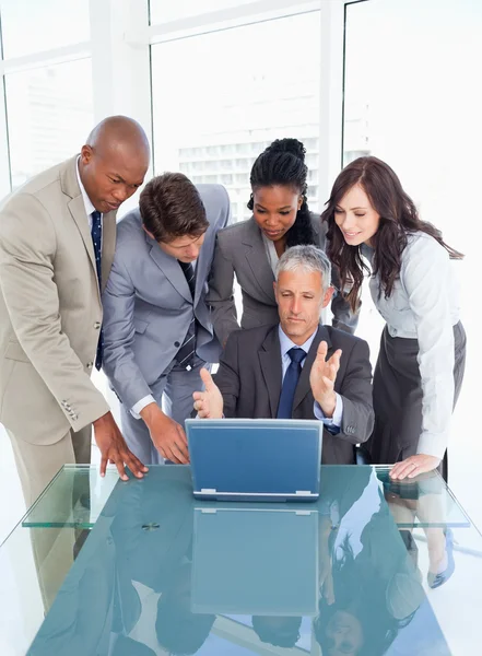 Mature and serious manager giving explanations to his team with Stock Photo