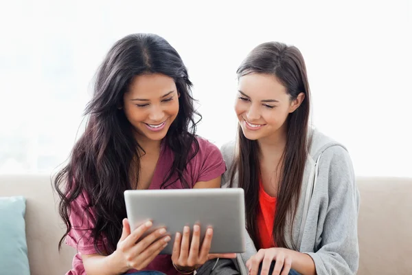 Una mujer con su amiga sonriendo mientras ambos miran la tableta —  Fotos de Stock