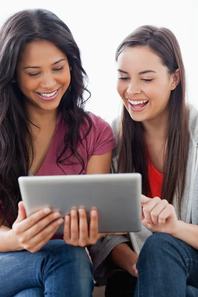 Nahaufnahme in halber Länge von zwei lachenden Frauen, die einen Tab betrachten — Stockfoto