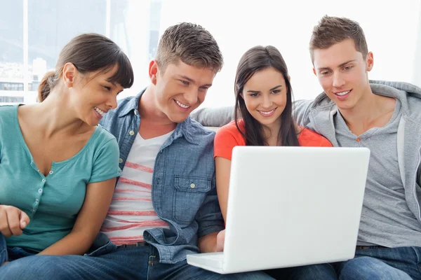 Een lachende groep vrienden zitten rond een laptop — Stockfoto