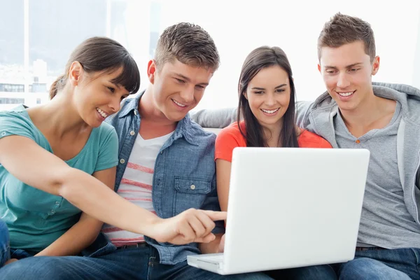 Um grupo sorridente de amigos olhando para o laptop com uma menina p — Fotografia de Stock
