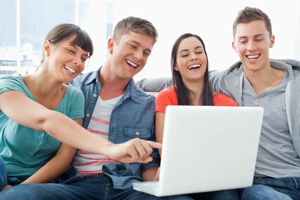 Un groupe d'amis souriants réunis autour d'un ordinateur portable — Photo