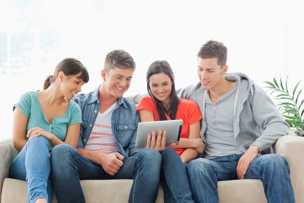 Een groep van vrienden zitten op de Bank tijdens het kijken naar een tablet pc — Stockfoto