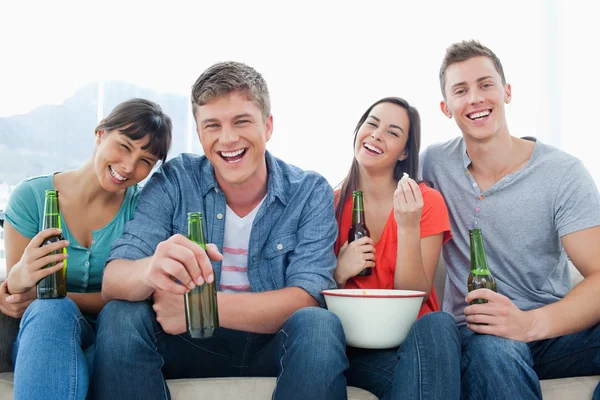 Смеющаяся группа сидит и наслаждается пивом и попкорном — стоковое фото