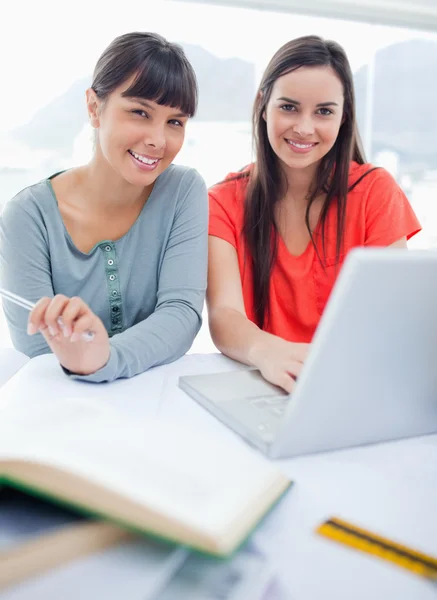 Close up shot of a girl and her friend smiling as they sit with — Stock Photo, Image
