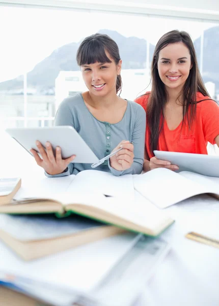 Twee studenten met tabletten in hun handen als ze zitten en thuis — Stockfoto