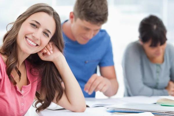 Een lachende vrouw rust haar hoofd op haar hand als ze naar de c kijkt — Stockfoto