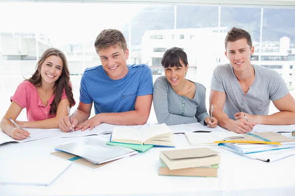 Vier lachende studenten opzoeken in de camera — Stockfoto