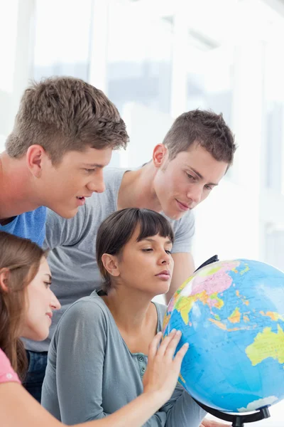 Four students looking at the globe — Stock Photo, Image