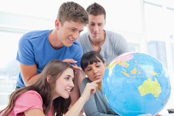 Studenti che puntano a luoghi del mondo su un globo — Foto Stock