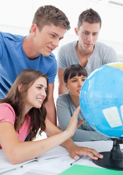 Primo piano di quattro guardando il globo del mondo — Foto Stock