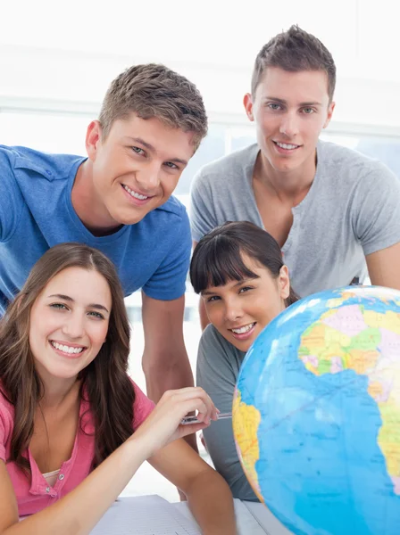 Een groep van vrienden naast een hele wereld op zoek naar de camera — Stockfoto