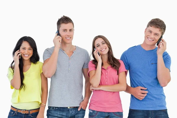 A smiling group of friends make calls while looking into the cam — Stock Photo, Image