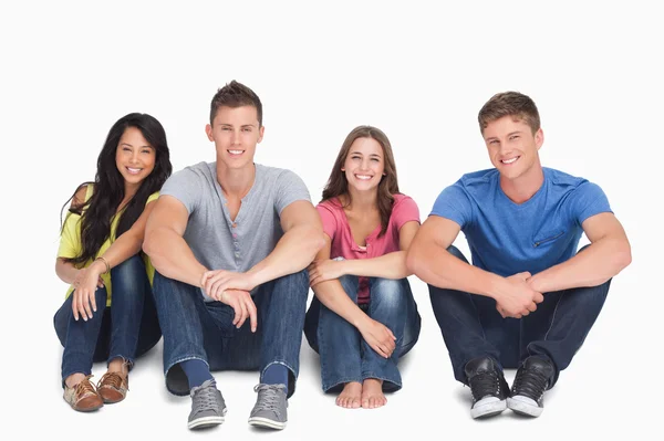 Sorrindo grupo sentado no chão com as mãos em sua le — Fotografia de Stock