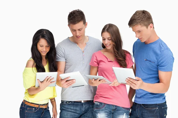 Quatro amigos olhando para seus tablets e sorrindo — Fotografia de Stock