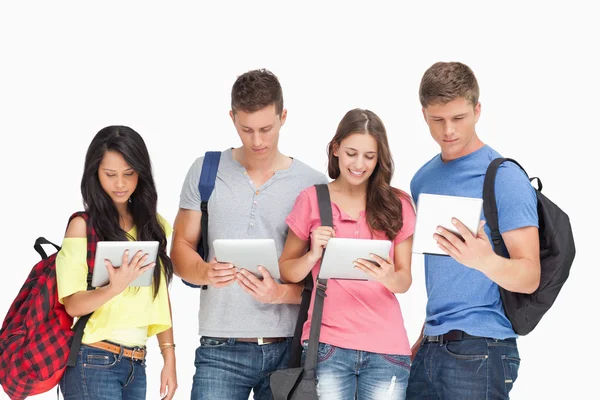 Estudantes com mochilas olhando para seus tablets — Fotografia de Stock