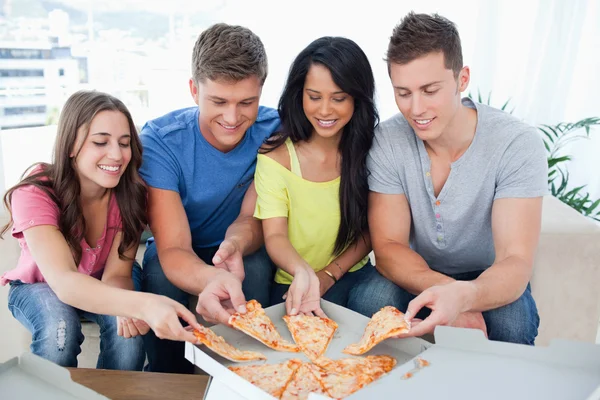 Freunde greifen nach einer Pizza, während sie auf die Schachtel schauen — Stockfoto