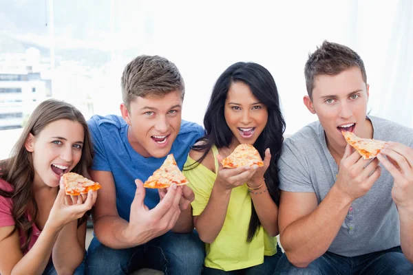 Bezig met eten van pizza als ze kijken naar de camera — Stockfoto