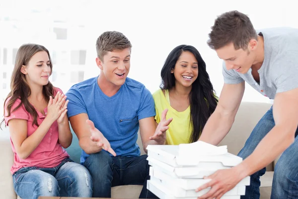 Friends celebrating as one guy brings pizza to them — Stock Photo, Image