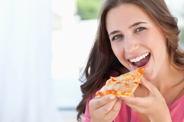 Una mujer con una rebanada de pizza en los labios — Foto de Stock