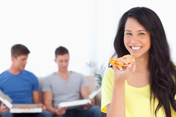 Mulher sorrindo e olhando para a câmera enquanto ela segura pizza — Fotografia de Stock