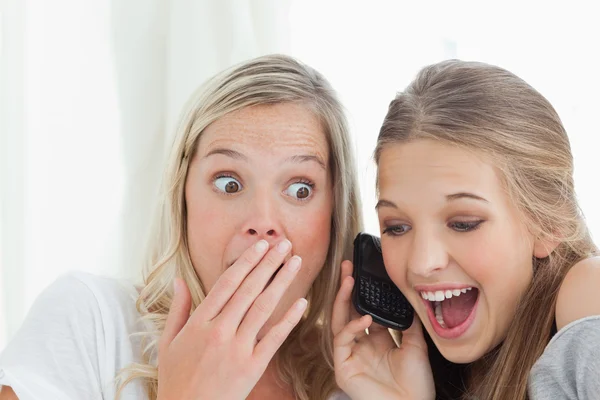 Geschokt en gelukkig zusters luisteren naar een telefoongesprek — Stockfoto