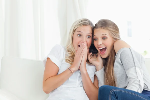 Un par de chicas impactadas y felices haciendo una llamada telefónica —  Fotos de Stock