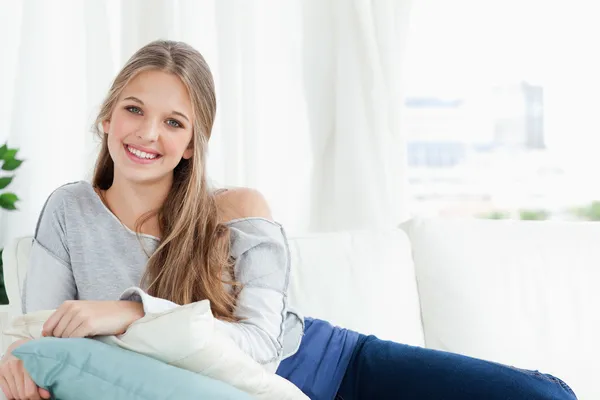 Lachende meisje liggend op de bank kijken naar de camera — Stockfoto