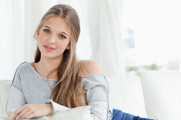 Een meisje liggend op de bank kijken naar de camera — Stockfoto