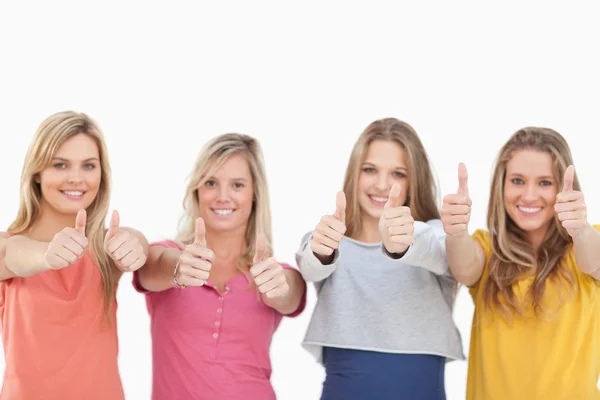 Четыре улыбающиеся девушки, показывающие большие пальцы — стоковое фото