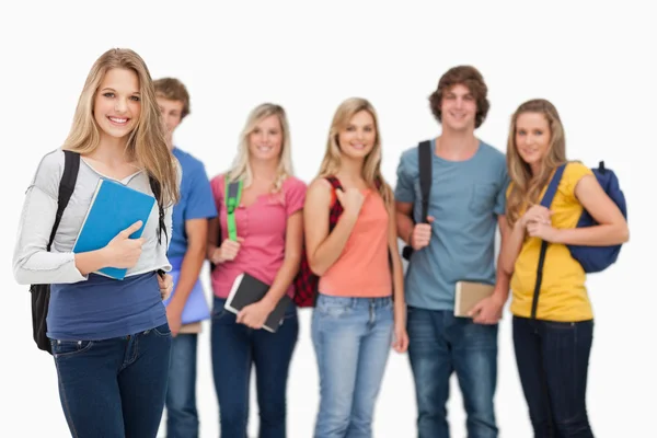 Una chica sonriente de pie frente a sus amigos — Foto de Stock