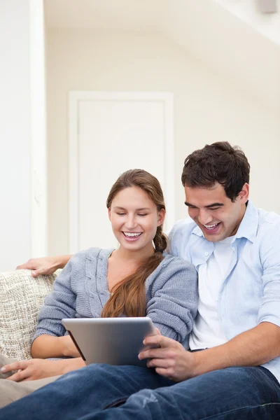 Pareja riendo mientras sostiene un portátil — Foto de Stock