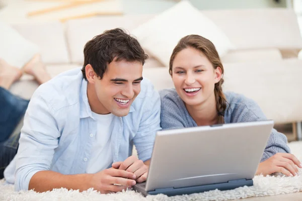 Pareja joven mintiendo mientras usa una computadora — Foto de Stock