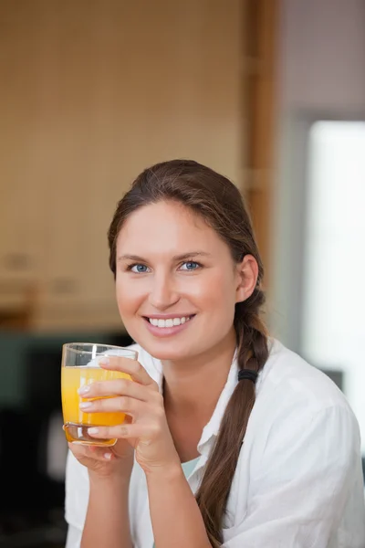 Γυναίκα πίνοντας χυμό πορτοκαλιού, ενώ χαμογελώντας — Φωτογραφία Αρχείου
