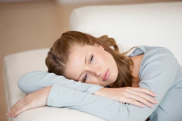 Femme allongée sur un canapé croisant les bras regardant vers le bas — Photo