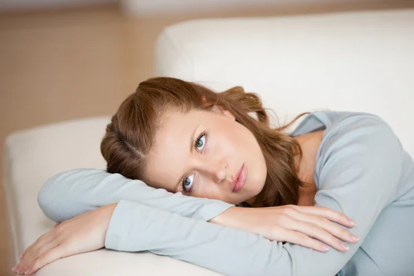 Woman crossing harms while lying on a sofa looking up — Stock Photo, Image