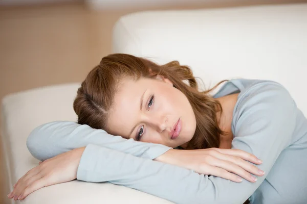 Vrouw liggen op een sofa overschrijding van haar armen — Stockfoto