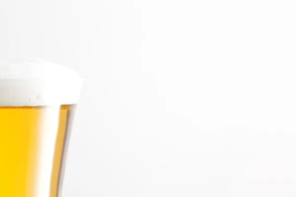Glas Bier und Schaum vor weißem Hintergrund — Stockfoto