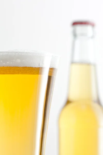 Copo e garrafa de cerveja contra um fundo branco — Fotografia de Stock