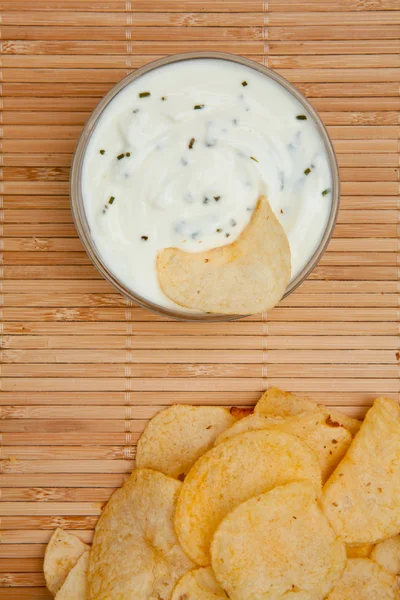 Close up of a bowl of dip with herbs beside chips — Stock Photo, Image