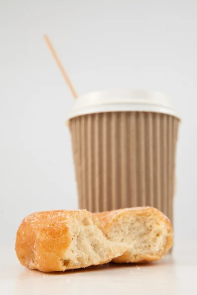Um donut meio comido e uma xícara de chá colocados juntos — Fotografia de Stock
