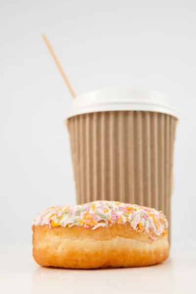 Um donut multicolorido e uma xícara de chá colocados juntos — Fotografia de Stock
