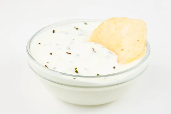 Bowl of white dip with herbs and a nacho dipped in it — Stock Photo, Image